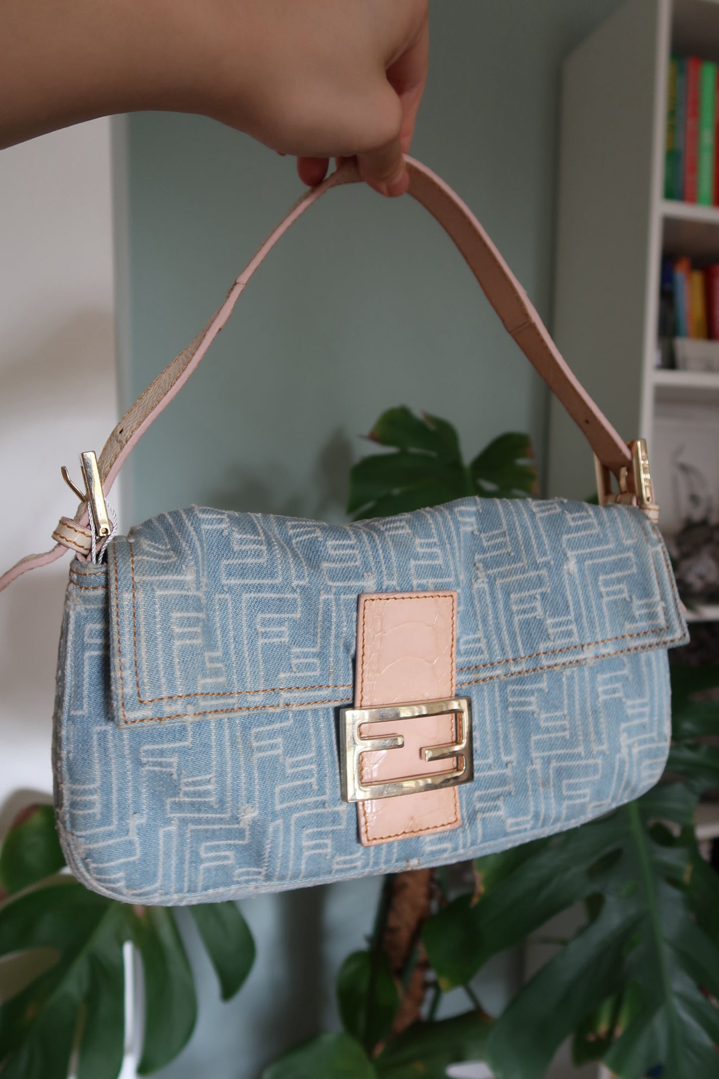 A vintage Fendi frayed denim baguette shoulder bag with a light blue denim body, leather details, and a gold-tone Fendi logo clasp.